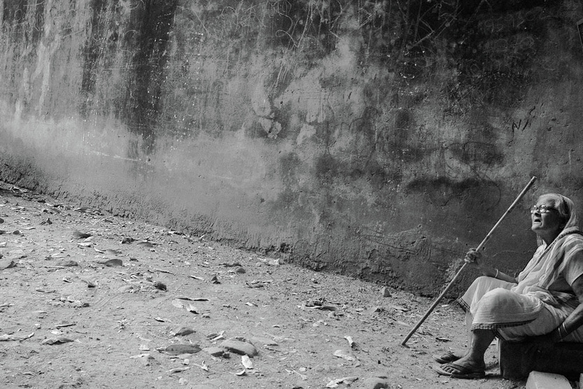 Picture of an Indian woman sitting amidst debris, against a tall, dirty wall.  An arresting and artistic image that underscores the desperate living conditions in parts of India.  Part of the Photographer Profiles series at FreePhotoCourse.com. © 2010, Soham Gupta, all rights reserved. 
