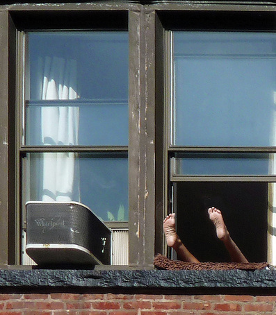 Picture of a man's legs and feet hanging out of a New York City apartment window. Photographed by Bobbie Turner, part of the FreePhotoCourse.com 'NYC Exposed' photography exhibit; all rights reserved.