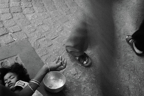 Picture of a child sleeping on the street in Calcutta, India, while the parent is begging for hand-outs.  Motion blur as people walk past this tearful scene.  Part of the Photographer Profiles series at FreePhotoCourse.com. © 2010, Soham Gupta, all rights reserved. 